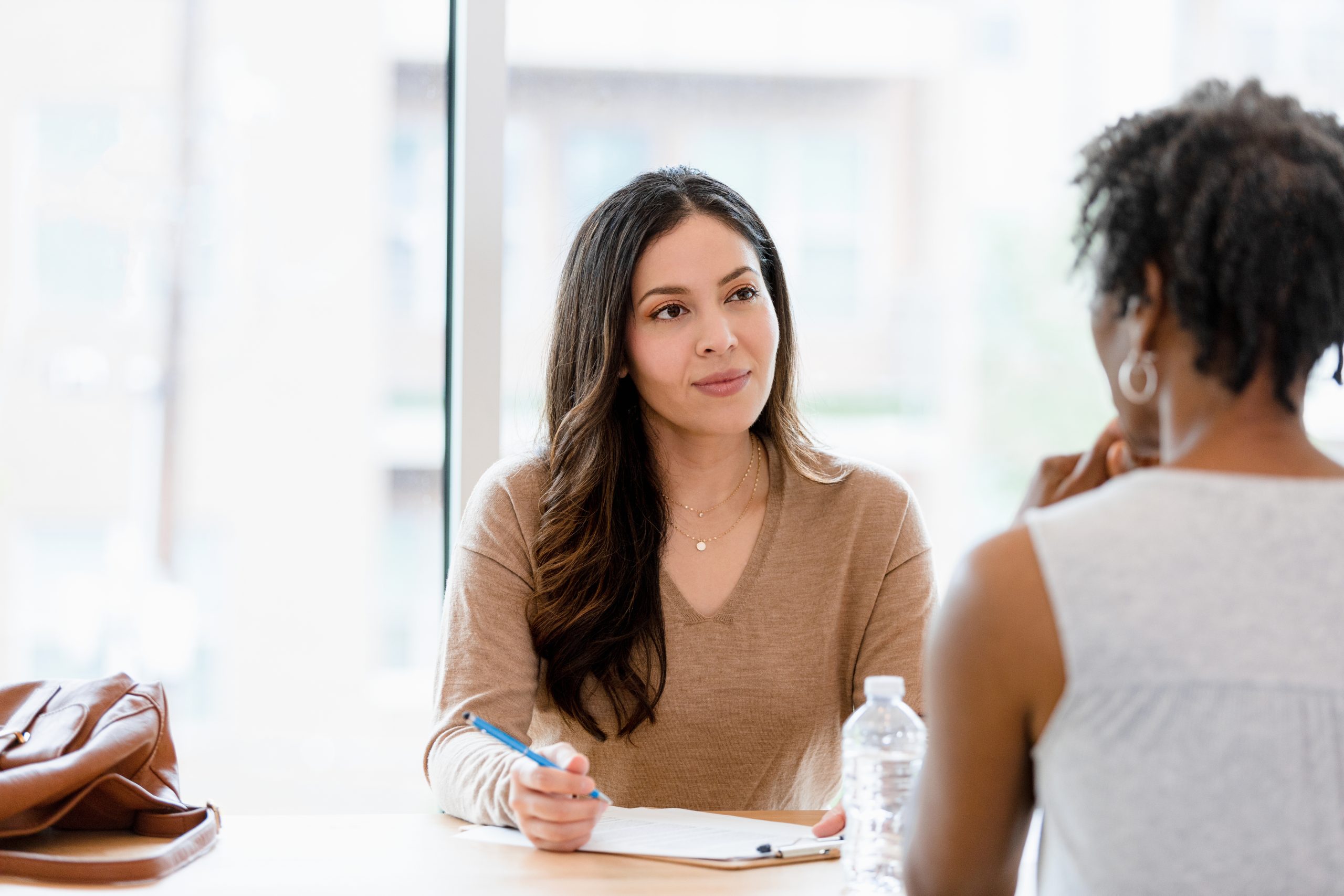 Mid adult female therapist listens to unrecognizable female client