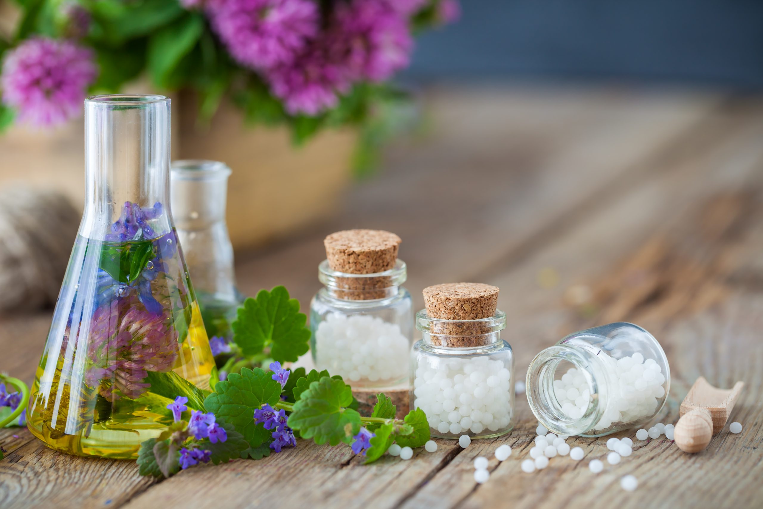 Vials of tincture or infusion of healthy herbs, bottles of homeopathy globules and healthy herbs on table. Alternative medicine concept.